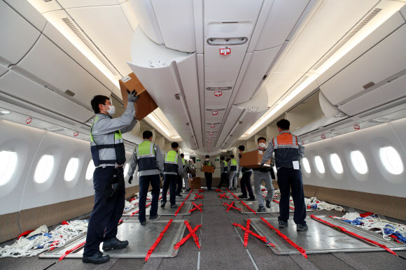24일 오후 인천국제공항 1터미널에서 아시아나항공 관계자들이 A350 여객기에 화물을 탑재하고 있다. 아시아나항공은 2분기 실적 호조세를 이어가기 위해 A350-900 여객기 1대의 이코노미 좌석 283석을 화물탑재 공간으로 개조했다. 이번 개조로 5톤의 추가 화물을 적재해 편당 23톤의 화물 수송이 가능하다. 2020.9.24  연합뉴스