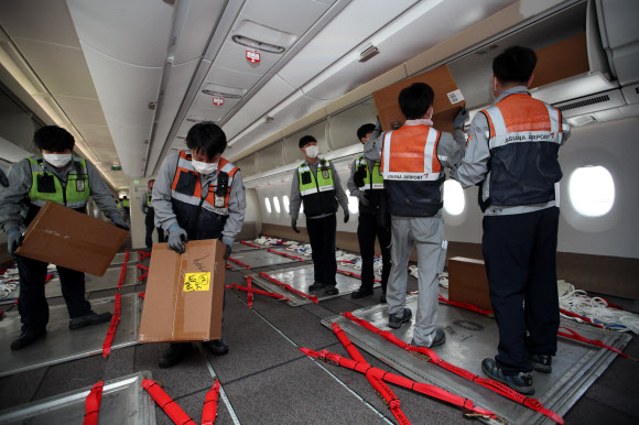 24일 오후 인천국제공항 1터미널에서 아시아나항공 관계자들이 A350 여객기에 화물을 탑재하고 있다. 아시아나항공은 2분기 실적 호조세를 이어가기 위해 A350-900 여객기 1대의 이코노미 좌석 283석을 화물탑재 공간으로 개조했다. 이번 개조로 5톤의 추가 화물을 적재해 편당 23톤의 화물 수송이 가능하다. 2020.9.24  연합뉴스