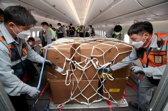 24일 오후 인천국제공항 1터미널에서 아시아나항공 관계자들이 A350 여객기에 화물을 탑재하고 있다. 아시아나항공은 2분기 실적 호조세를 이어가기 위해 A350-900 여객기 1대의 이코노미 좌석 283석을 화물탑재 공간으로 개조했다. 이번 개조로 5톤의 추가 화물을 적재해 편당 23톤의 화물 수송이 가능하다. 2020.9.24  연합뉴스