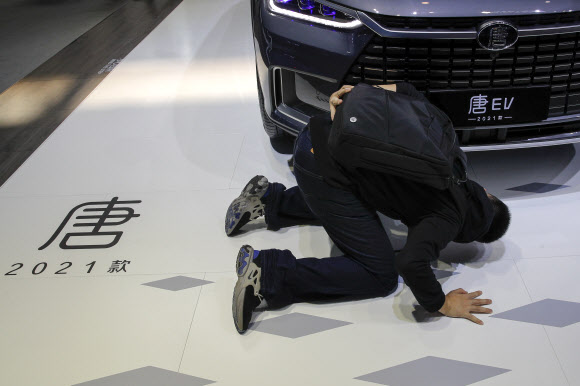 한 관람객이 지난달 27일 베이징 국제 모터쇼가 열리고 있는 베이징국제전시센터에서 비야디(BYD) 전기차 모델을 마치 큰절을 하듯 엎드려 살펴보고 바라보고 있다. 베이징 AP 연합뉴스
