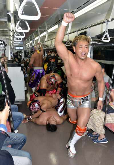 지난 3일 일본 후쿠시마와 니가타를 잇는 JR 타다미선에서 열린 프로레슬링 대회에서 선수들이 승객들 사이에서 열띤 경기를 하고 있다. 2020.10.7  교도 연합뉴스