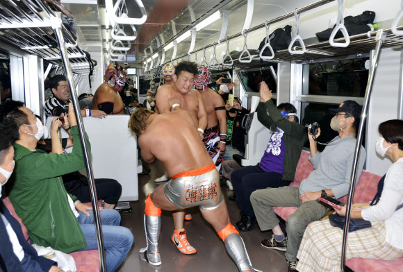 지난 3일 일본 후쿠시마와 니가타를 잇는 JR 타다미선에서 열린 프로레슬링 대회에서 선수들이 승객들 사이에서 열띤 경기를 하고 있다. 2020.10.7  교도=연합뉴스