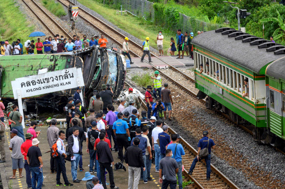 태국 관리들과 구경꾼들이 11일 수도 방콕의 동쪽 차초엔사오 지방의 클롱 콰엥 클란 철도역 근처에서 열차에 치여 전복된 버스 잔해 근처에 모여 있다. 방콕 AFP 연합뉴스 