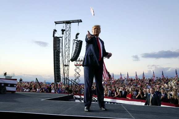 도널드 트럼프 대통령이 12일(현지시간) 미국 플로리다주 올랜도 샌포드 국제공항의 유세장에 도착해 쓰고 있던 마스크를 군중 속으로 던지고 있다. AP 연합뉴스