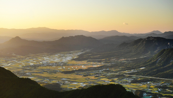미녀산 너머로 노랗게 물든 가조분지가 강처럼 흘러가고 있다. 이 계절에만 마주할 수 있는 풍경의 성찬이다. 사진 오른쪽은 일본 왕실의 조상 전설이 전하는 우두산, 왼쪽에 뾰족 솟은 산은 보해산이다. 합천 오도산에서 본 풍경이다.