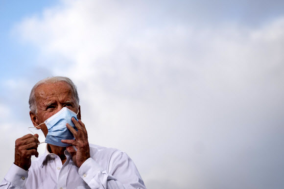 조 바이든 미국 민주당 대통령 후보가 27일(현지시간) 조지아주의 애틀랜타에서 열린 드라이브인 형태의 유세에서 연설하기 직전 마스크를 벗기고 있다.  애틀랜타 로이터 연합뉴스