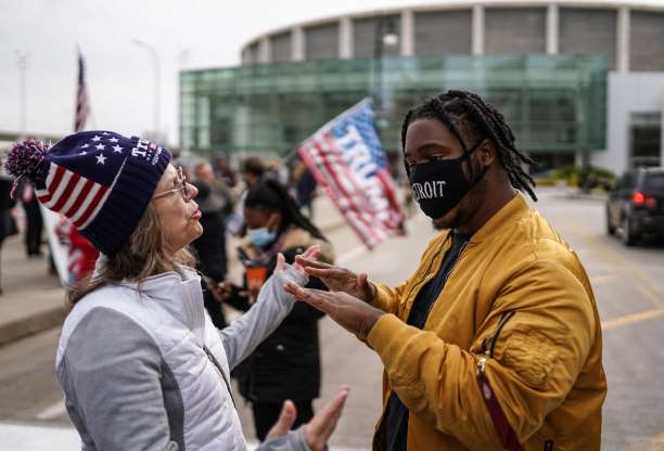 미 대선이 끝난지 이틀이 지난 5일(현지시간) 미시간주 드트로이트에서 트럼프 지지 모자를 쓴 여성과 마스크를 쓴 바이든 지지자가 입씨름을 하고 있다. 디트로이트 AP 연합뉴스