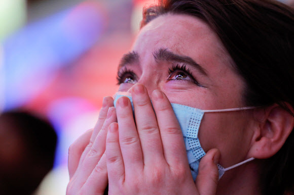 7일(현지시간) 미국 뉴욕 타임스스퀘어에서 한 시민이 조 바이든 대통령 당선인의 승리 연설을 보며 눈물을 흘리고 있다. 로이터 연합뉴스
