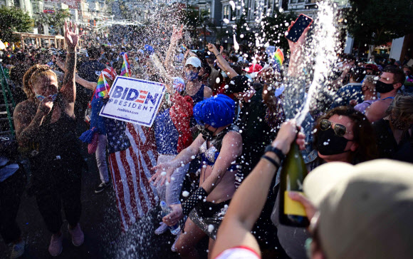 7일(현지시간) 미국 캘리포니아주 샌프란시스코의 카스트로 지구에서 조 바이든이 미국 대통령으로 당선된 것을 축하하기 위해 사람들이 거리에서 샴페인을 뿌리고 춤을 추고 있다. AFP 연합뉴스
