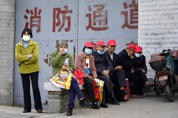 6일 중국 베이징의 한 거리에 지방에서 올라온 관광객들이 마스크를 쓴 채 앉아 있다. 2020.11.6  AP 연합뉴스