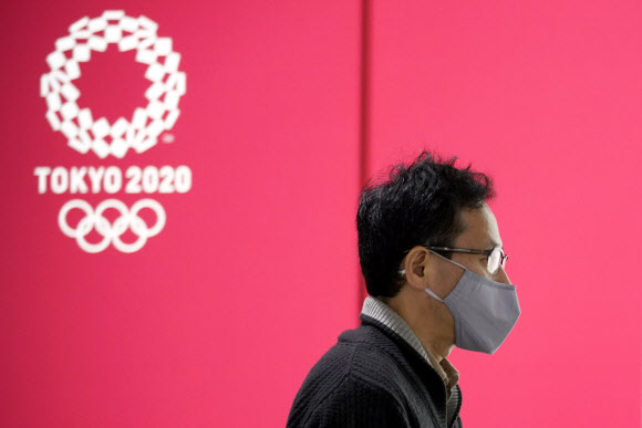 일본 도쿄에서 마스크를 쓴 남성이 12일 2020년 도쿄올림픽 광고가 나오는 전광판 앞을 지나고 있다. 2020.11.12  EPA 연합뉴스