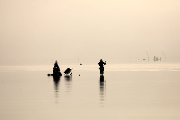 산타클로스 의상을 입은 한 남성이 15일(현지시간) 이스라엘 아인 보크크 인근 사해 성지의 소금 위에서 이스라엘 관광부가 주최한 크리스마스 맞이 비디오 촬영을 위해 크리스마스 트리 옆에 앉아 포즈를 취하고 있다. 이스라엘 관광부는 코로나19로 인해 관광이 심각한 타격을 입었다고 밝혔고 이스라엘은 코로나19 위기 속에서 휴가철을 준비하고 있다. EPA 연합뉴스
