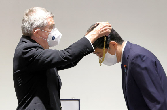 토마스 바흐 국제올림픽위원회(IOC) 위원장이 16일 오후 도쿄 신주쿠 올림픽 박물관에서 아베 신조 전 일본 총리에게 올림픽 발전에 기여한 인사에게 주는 ‘올림픽 훈장’을 목에 걸어 주고 있다. 2020.11.16  교도 연합뉴스