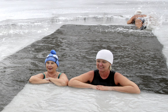 지역 냉수 훈련과 겨울 수영 공동체의 여성들이 21일(현지시간) 러시아 노보시비르스크의 꽁꽁 언 블라이우드세 호수 속에서 휴식을 취하고 있다. 타스 연합뉴스
