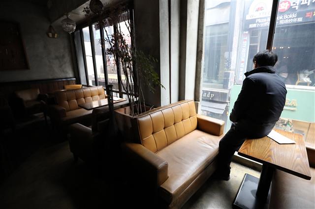 수도권 지역의 사회적 거리두기가 2단계로 격상된 24일 장사를 접은 서울 중구의 한 카페에서 주인이 창밖을 바라보고 있다. 사회적 거리두기가 2단계로 격상된 이날부터 유흥시설은 운영할 수 없고 카페는 포장과 배달만, 음식점은 오후 9시부터 포장, 배달만 할 수 있다.  뉴스1