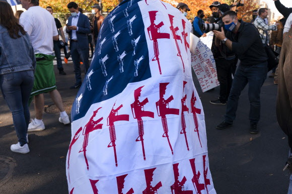 지난 13일(현지시간) 한 트럼프 지지자가 미국 워싱턴DC 집회에서 총기로 성조기처럼 꾸민 깃발을 몸에 둘렀다. AP