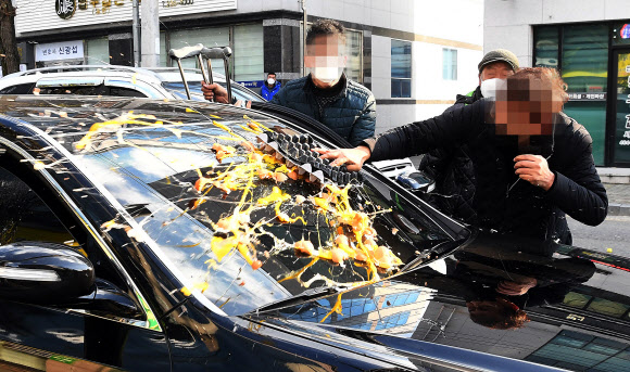 전두환 전 대통령이 30일 광주지방법원에서 열린 ‘회고록 형사재판’ 1심 선고 공판의 출석을 위해 탑승했던 검은색 승용차에 광주시민이 계란을 던지고 있다. 5·18 민주화운동 관련 단체 회원은 전씨가 이날 징역 8개월에 집행유예 2년의 유죄 판결을 받은 뒤 다른 차를 타고 광주법원을 빠져나가자 사죄를 요구하며 빈 차에 계란과 밀가루를 던졌다. 2020.11.30  연합뉴스
