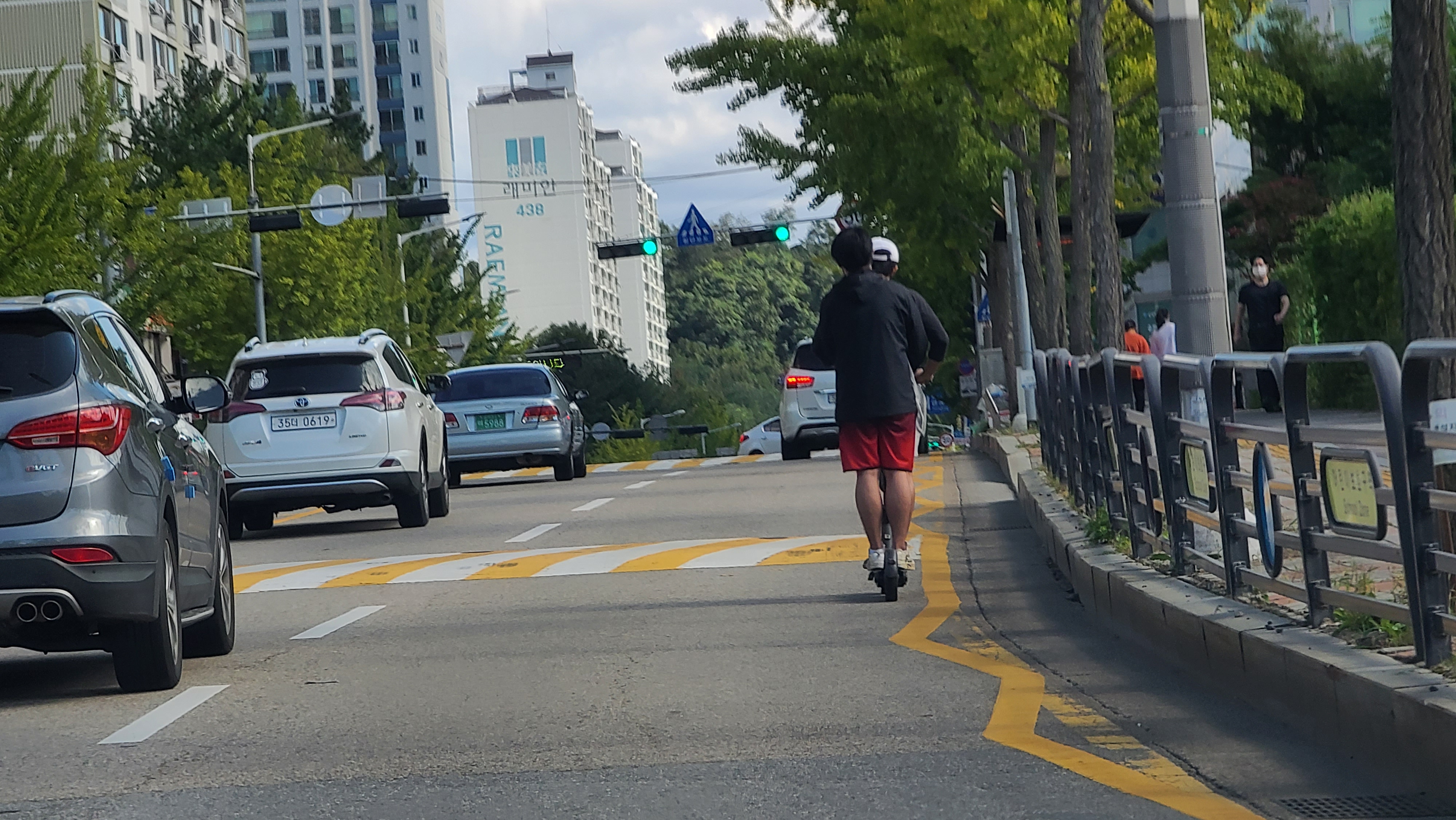 수원시 영통구 한 도로에서 청년 2명이 전동킥보드를 타고 도로를 주행하고 있다. 