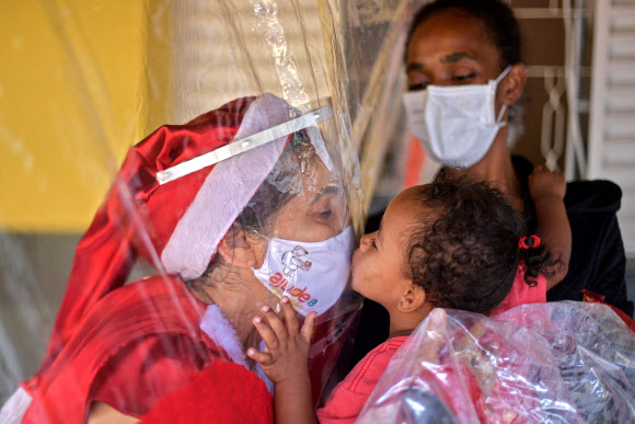 비닐 장막 사이 두고 자원봉사자와 감사 키스하는 브라질 어린이