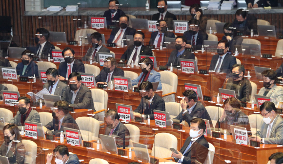 국민의 힘 의원들이 9일 오후 좌석 앞에 ‘공수처법 저지’등의 손피켓을 붙이고 본회의에 참석하고 있다.2020. 12. 9 정연호 기자tpgod@seoul.co.kr
