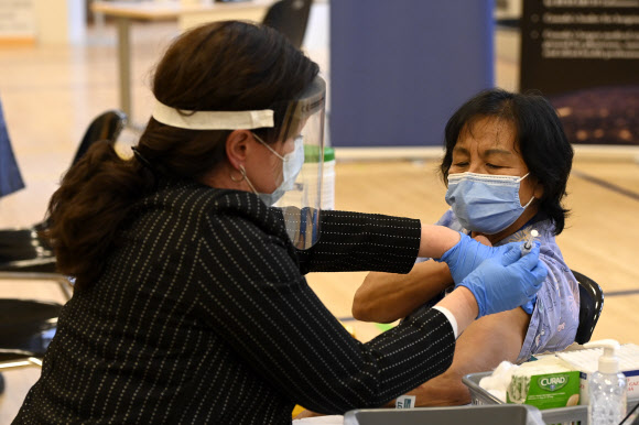 14일(현지시간) 캐나다 토론토의 한 요양병원에서 일하는 간호사 아니타 퀸단젠이 캐나다 최초로 코로나19 백신을 접종받고 있다. 캐너디언 프레스 제공 AP 연합뉴스 