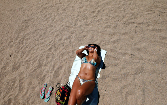 한 여성이 14일(현지시간) 칠레 발파라이소의 해변에서 특수 안경을 쓰고 일식을 관측하고 있다. 로이터 연합뉴스