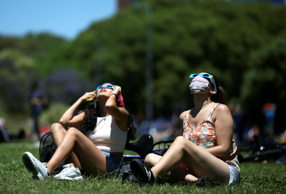 14일(현지시간) 아르헨티나 부에노스 아이레스에서 시민들이 특수 안경을 쓰고 일식을 관측하고 있다. 로이터 연합뉴스