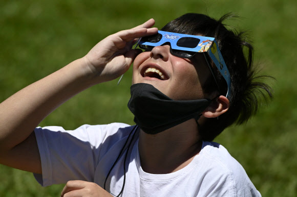 한 소년이 14일(현지시간) 아르헨티나 부에노스 아이레스에서 특수 안경을 쓰고 일식을 관측하고 있다. AFP 연합뉴스