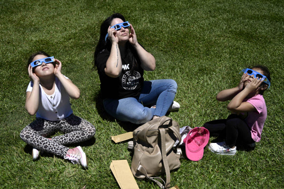 한 가족이 14일(현지시간) 아르헨티나 부에노스아이레스 갈릴레오 갈릴레이 플라네타륨에서 일식을 관측하고 있다. AFP 연합뉴스