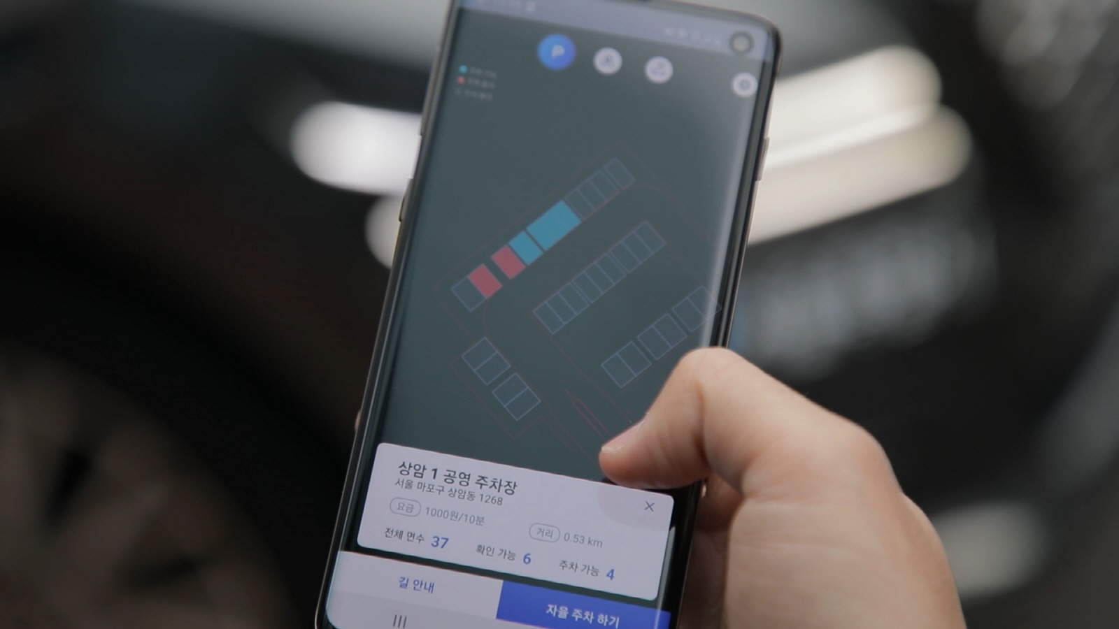 LG유플러스 관계자가 모바일 앱을 통해 주차장 빈 자리를 선택해 5세대(5G) 이동통신 자율주행차 ‘에이원(A1)’가 스스로 주차할 수 있도록 하는 모습. LG유플러스 제공