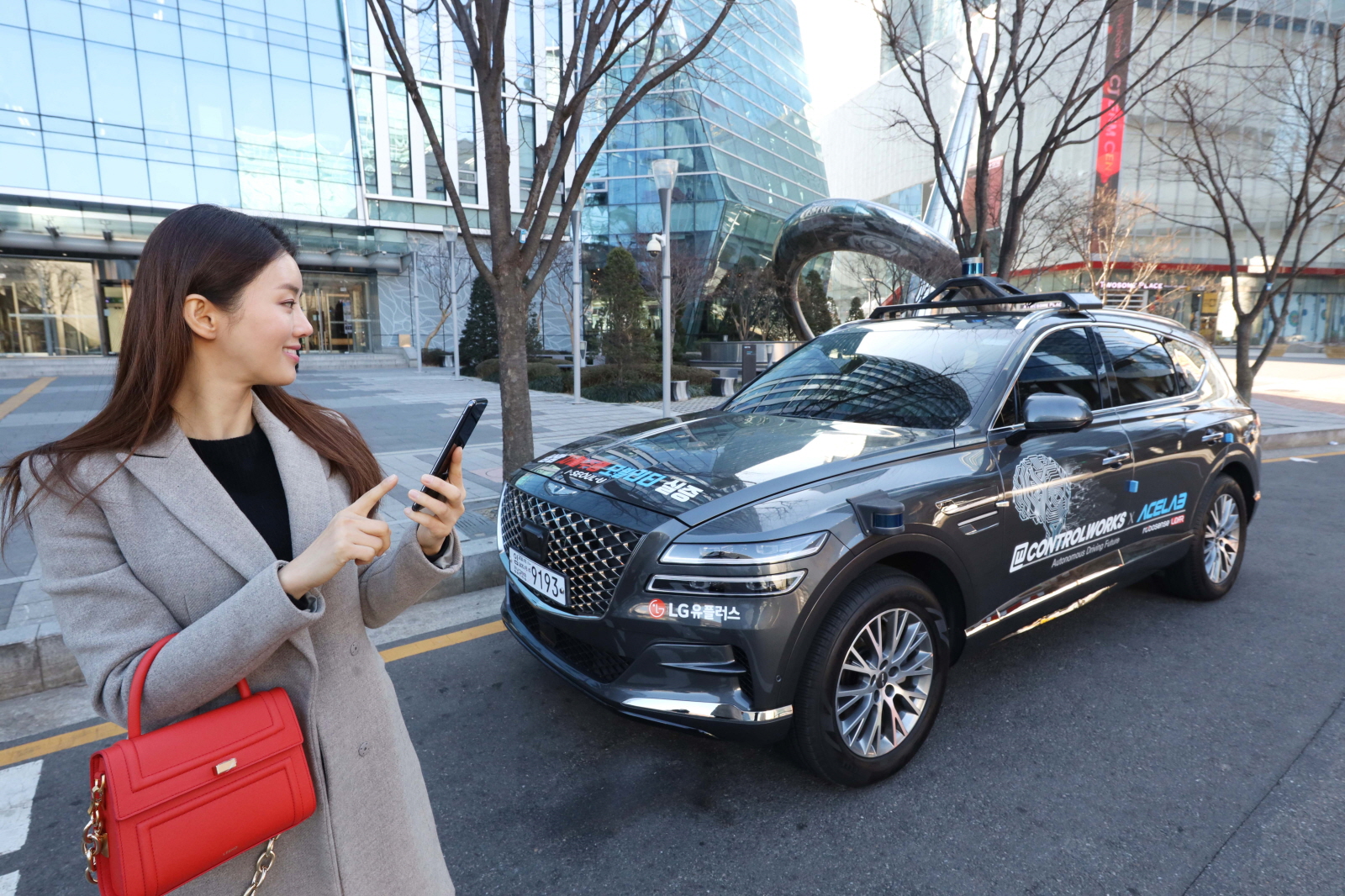 LG유플러스 모델이 서울 마포구 상암동 자율주행 시범지구에서 모바일 앱을 이용해 5세대(5G) 이동통신 자율주행차 ‘에이원(A1)’을 인근 주차장으로 보내 스스로 주차하도록 하는 모습. 　LG유플러스 제공