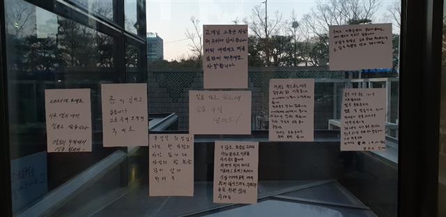 지난 16일 서울 여의도 LG트윈타워 사옥 로비 유리문에 청소노동자들이 작성한 집단해고 철회 선전물이 붙어 있다.