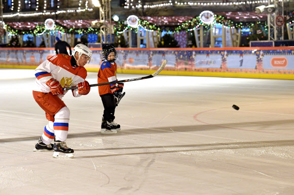 블라디미르 푸틴 러시아 대통령(왼쪽)이 21일(현지시간) 러시아 모스크바의 붉은광장 아이스스케이트장에서 열린 크리스마스 트리 오브 위시 캠페인(the Christmas Tree of Wishes campaign) 중, 어린이와 아이스하키를 하고 있다. 블라디미르 푸틴 러시아 대통령은 크리스마스와 새해를 앞두고 러시아 아이들의 소원을 들어준다. 타스 연합뉴스
