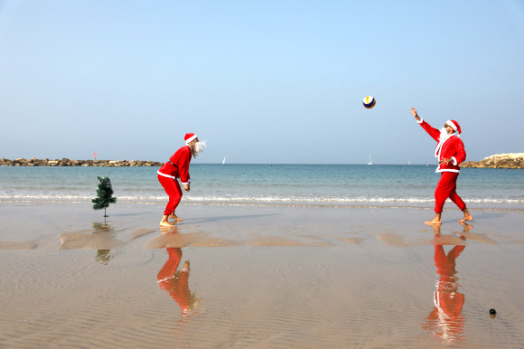 산타클로스 복장을 한 이스라엘인들이 22일(현지시간) 이스라엘 텔아비브 해변에서배구를 하고 있다. 이 행사는 다가오는 크리스마스 휴일을 앞두고 텔아비브 시에서 주최했다. EPA 연합뉴스