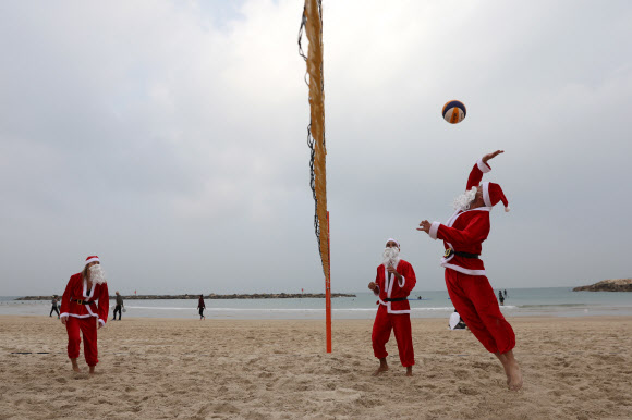 산타클로스 복장을 한 이스라엘인들이 22일(현지시간) 이스라엘 텔아비브 해변에서배구를 하고 있다. 이 행사는 다가오는 크리스마스 휴일을 앞두고 텔아비브 시에서 주최했다. EPA 연합뉴스