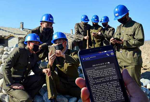 수해 복구 중 휴대전화로 위문편지 읽는 북한 인민군
