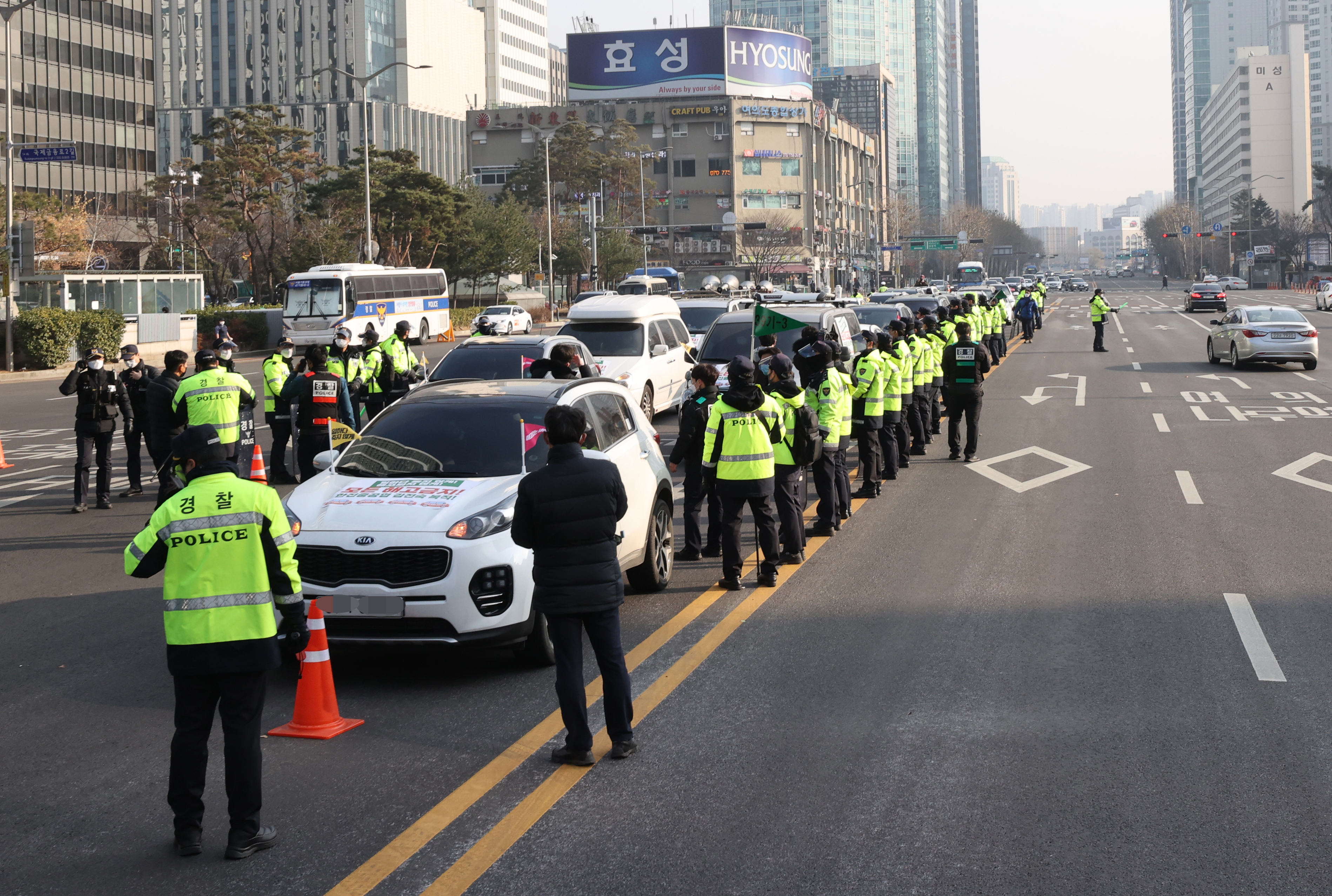 26일 오후 서울 여의도역 부근 도로에서  중대재해법 입법과 비정규직 해고 금지, 김진숙 민주노총 부산본부 지도위원의 복직 등을 요구하는 차량시위가 경찰에 가로막혀 있다.  ‘비정규직이제그만’ 등 노동?시민단체들로 구성된 ‘생명을 살리고 해고를 멈추는 240 희망차량행진 준비위원회’는 경찰의 집회 금지통고에도 불구하고 행진을 강행했다. 이 단체는 여의도 전경련회관 앞에서 기자회견을 열고 “전경련 앞에서 출발하는 행진은 취소하지만 서울 세 곳에서 행진을 시작했다”고 밝혔다.  2020.12.26 연합뉴스