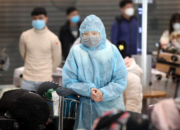 영국발 변이 코로나19 바이러스가 국내에서 확인되는 등 코로나19 확산이 계속되고 있는 28일 오전 인천국제공항 1터미널 입국장에서 방호복을 입은 해외 입국객이 대기하고 있다. 2020.12.28  연합뉴스