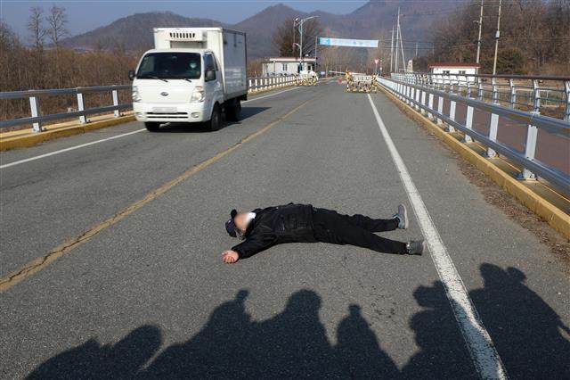 28일 오전 서울 동부구치소에서 신종 코로나바이러스 감염증(코로나19) 확진 판정을 받은 수용자를 태운 버스가 경북 청송군 경북북부 제2교도소로 출발했다는 소식이 전해진 가운데 자신을 청송군 주민이라고 밝힌 한 남성이 확진자 수용에 반대하며 도로를 가로막고 누워 있다. 2020.12.28 뉴스1