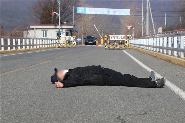 28일 오전 서울 동부구치소에서 신종 코로나바이러스 감염증(코로나19) 확진 판정을 받은 수용자를 태운 버스가 경북 청송군 경북북부 제2교도소로 출발했다는 소식이 전해진 가운데 자신을 청송군 주민이라고 밝힌 한 남성이 확진자 수용에 반대하며 도로를 가로막고 누워 있다. 2020.12.28 뉴스1