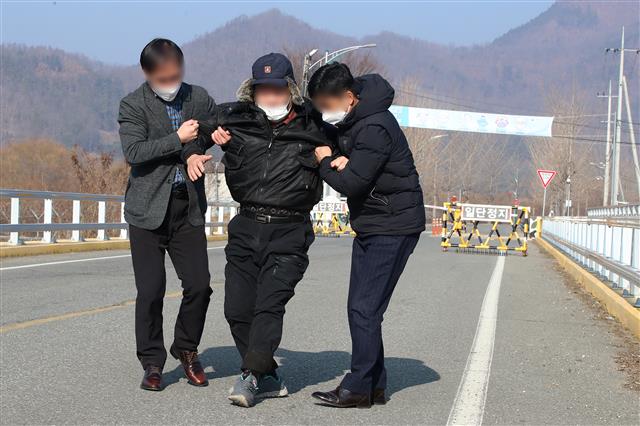 28일 오전 서울 동부구치소에서 신종 코로나바이러스 감염증(코로나19) 확진 판정을 받은 수용자를 태운 버스가 경북 청송군 경북북부 제2교도소로 출발했다는 소식이 전해진 가운데 한 남성이 확진자 수용에 반대하며 도로를 가로막고 누워 현장에 배치된 경찰이 설득해 이동시키고 있다. 2020.12.28 뉴스1