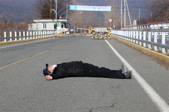 28일 오전 서울 동부구치소에서 신종 코로나바이러스 감염증(코로나19) 확진 판정을 받은 수용자를 태운 버스가 경북 청송군 경북북부 제2교도소로 출발했다는 소식이 전해진 가운데 자신을 청송군 주민이라고 밝힌 한 남성이 확진자 수용에 반대하며 도로를 가로막고 누워 있다. 2020.12.28 뉴스1
