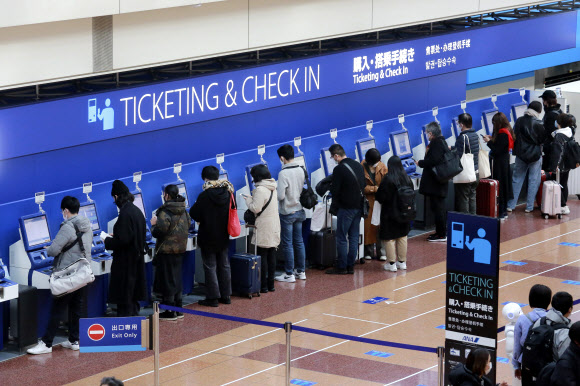 일본 도쿄 하네다 공항의 국내선 예매 창구에서 29일 승객들이 발권을 하고 있다. 2020.12.29  AP 연합뉴스