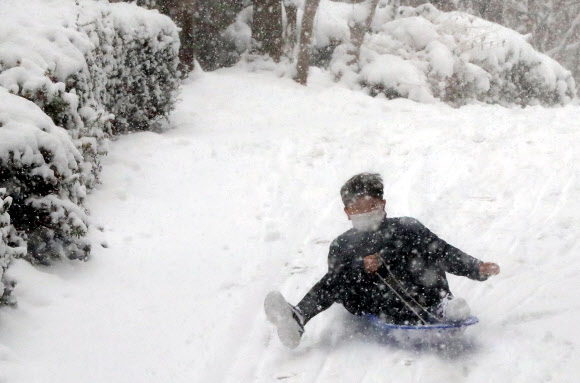광주와 전남 일부 지역에 대설주의보가 발효된 30일 광주 북구 운암동의 한 아파트 단지 내 언덕길에서 한 아이가 썰매를 타고 있다. 2020.12.30  연합뉴스