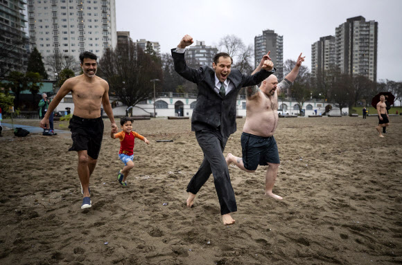 제이슨 루드는 1일(현지시간) 캐나다 브리티시컬럼비아주 밴쿠버의 잉글리시 베이에서 열린 새해맞이 북극곰 수영대회에서 30년차 참가를 축하하며 양복과 넥타이를 매고 물 속으로 뛰어 들었다. AP 연합뉴스