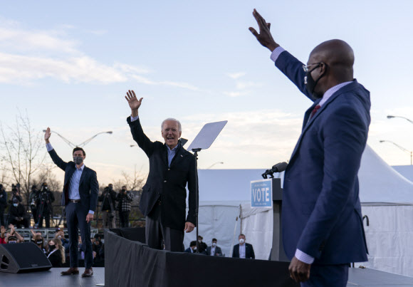 조 바이든 미국 대통령 당선인이 5일 조지아주 상원의원 결선 투표에 나서는 현역 의원 라파엘 워녹(오른쪽), 존 오소프와 함께 애틀랜타 연단 위에서 손을 흔들어보이고 있다. 애틀랜타 AP 연합뉴스 