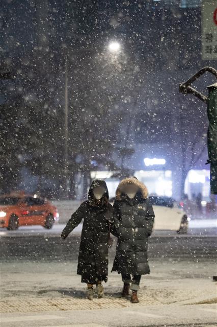 북극발 찬공기 영향으로 중부지역과 내륙을 중심으로 한파가 이어지고 있는 6일 저녁 서울 종로1가에서 시민들이 눈발을 헤치고 퇴근길 발걸음을 재촉하고 있다.  기상청 관계자는 “서울을 포함한 수도권은 퇴근시각이 눈이 내리는 때와 겹치면서 빙판길로 인한 차량지체 심할수 있으니 유의할 것”을 당부했다. 2021.1.6 뉴스1