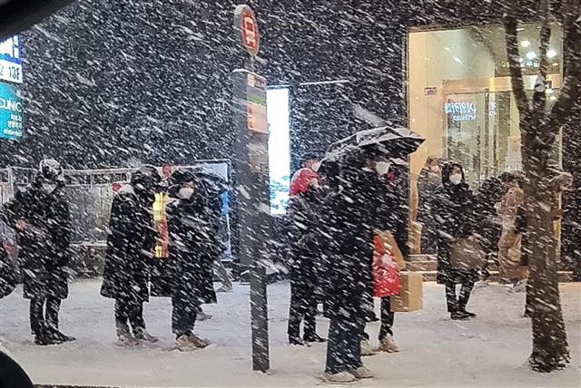 북극발 찬공기 영향으로 중부지역과 내륙을 중심으로 한파가 이어지고 있는 6일 저녁 서울 강남역 인근에서 시민들이 눈발을 맞으며 버스를 기다리고 있다.  기상청 관계자는 “서울을 포함한 수도권은 퇴근시각이 눈이 내리는 때와 겹치면서 빙판길로 인한 차량지체 심할수 있으니 유의할 것”을 당부했다. 2021.1.6 뉴스1