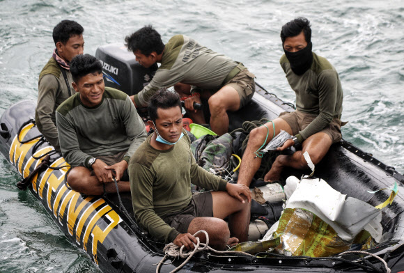 인도네시아 해군들이 10일(현지시간) 스리위자야항공 SJ182편 여객기가 추락한 것으로 추정되는 자카르타 앞바다에서 수거한 잔해들을 운반하고 있다. AP 연합뉴스