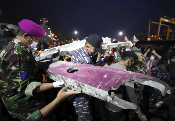인도네시아 군인과 구조대원들이 10일(현지시간) 자카르타 탄중프리오크항에서 추락한 스리위자야항공 SJ182편 여객기 잔해들을 운반하고 있다.  AP 연합뉴스